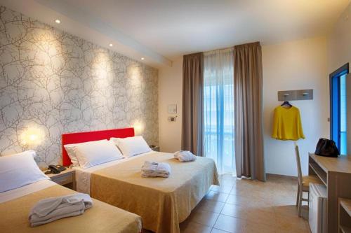 a hotel room with two beds and a window at Hotel Mimosa in Riccione