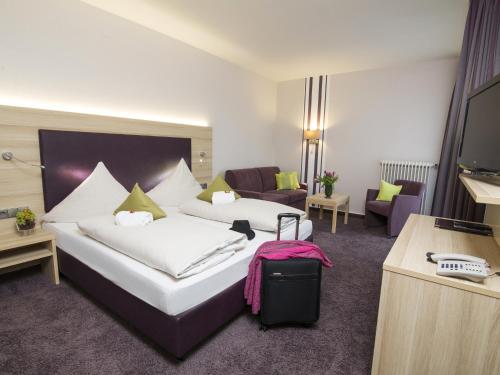 una camera d'albergo con due letti e una televisione di Concorde Hotel am Leineschloss ad Hannover