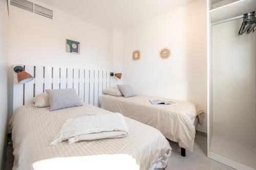 Duas camas num quarto com paredes brancas em Résidence Pierre et Vacances Cap Cassis Calanques em Roquefort-la-Bédoule