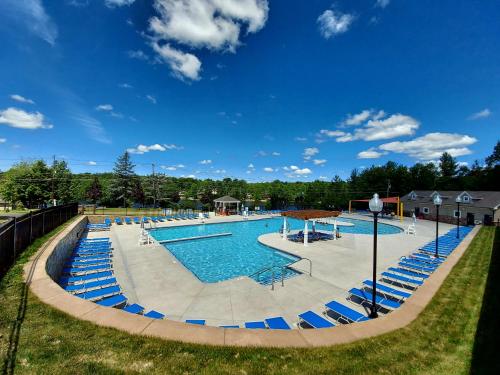 a large swimming pool with blue chairs and water at Chalet renovated Near Casino, Camelback , Kalahari 4bdrms firepit hot tub game room in Tobyhanna