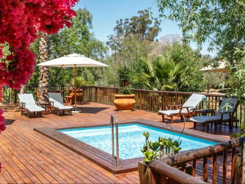 a pool on a deck with chairs and an umbrella at Gumtree Guest House in Oudtshoorn