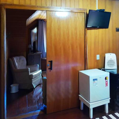 a room with a door and a chair and a television at Pousada Casa dos Sonhos in Campos do Jordão