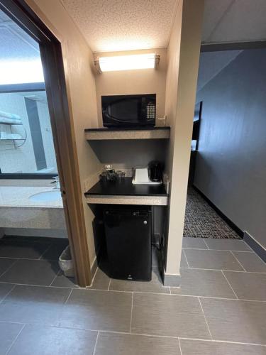 a room with a microwave and a kitchen with a sink at Wingate by Wyndham Lake George in Lake George