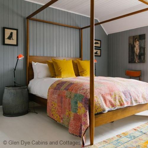 a bedroom with a canopy bed with yellow pillows at Cuttieshillock in Banchory