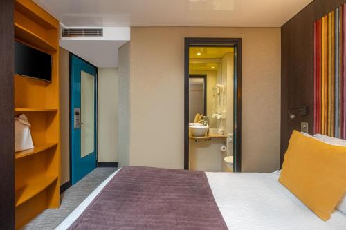 a hotel room with a bed and a bathroom at Hôtel Du Vieux Saule in Paris