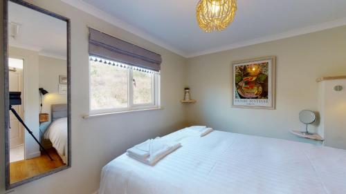 um quarto com uma cama branca e um espelho em E48 Redville, Riviere Towans em Hayle