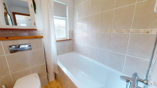 a bathroom with a white tub and a toilet at E48 Redville, Riviere Towans in Hayle