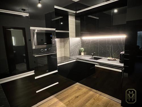 a black kitchen with a sink and a microwave at MM Residence in Cluj-Napoca