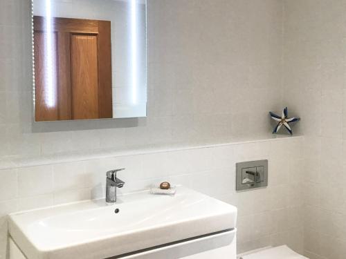 a white bathroom with a sink and a mirror at Ebbas Neuk in Beadnell