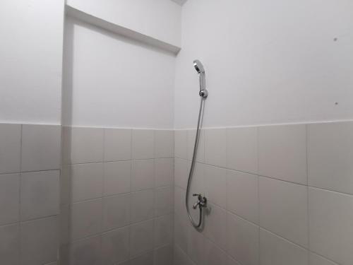 a shower in a white tiled bathroom at Mailbox Arsakha Lobi B Cibubur Village in Cibubur