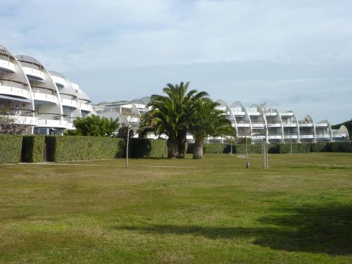 un parc avec des palmiers en face d'un bâtiment dans l'établissement AS22947-Studio cabine résidence direct sur plage, au Grau-du-Roi