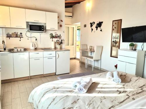 a kitchen with white cabinets and a large bed in a room at Studio Apartment Lino in Skrbčići