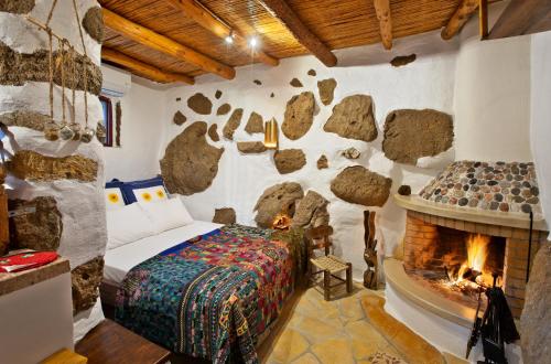 een slaapkamer met een stenen muur, een bed en een open haard bij Natura cottages in Makry Gialos