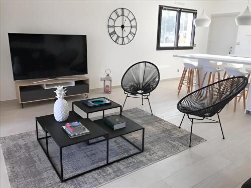 ein Wohnzimmer mit einem TV, 2 Stühlen und einem Tisch in der Unterkunft Sweet Holiday in Porto-Vecchio
