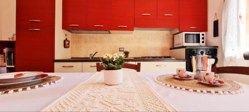 a kitchen with red cabinets and a table with flowers at Domu Irene - Triei in Triei