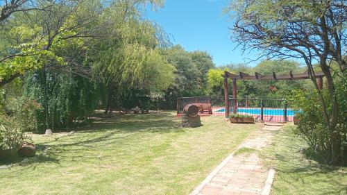 um jardim com uma piscina e uma pérgola de madeira em Cabañas SHAMBALLA em Cafayate