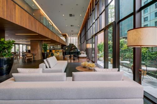 a lobby with white couches and a piano at Qoya São Paulo Paulista, Curio Collection by Hilton in Sao Paulo