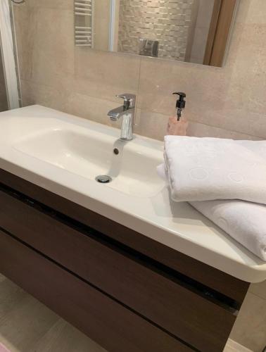La salle de bains est pourvue d'un lavabo blanc et d'un miroir. dans l'établissement S+3 luxurious apartment Hermes design in les jardins de Carthage Lac2, à Sidi Daoud
