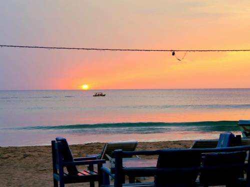 a group of chairs on the beach at sunset at Vitamin Sea Beach Cabana in Nilaveli