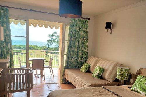 a living room with a couch and a table and a window at Studio avec vue mer exceptionnelle, plage et piscine, Village Vacances Sainte-Anne in Sainte-Anne