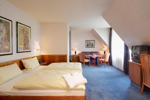 a hotel room with two beds and a table at Hotel-Gasthof Die Post Brennerei Frankenhöhe in Schillingsfürst