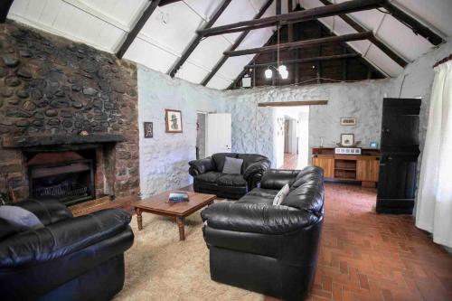 a living room with leather furniture and a stone fireplace at Bergwinds in Underberg