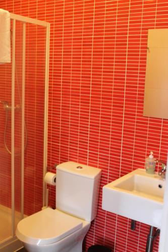 a red tiled bathroom with a toilet and a sink at Aveiro Rossio Hostel in Aveiro