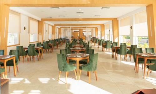 a dining room with tables and green chairs at Marom Port Said Resort & Beach in Port Said