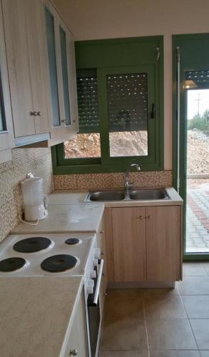 a kitchen with a stove and two sinks and a window at Porto Katsiki Blu in Athani