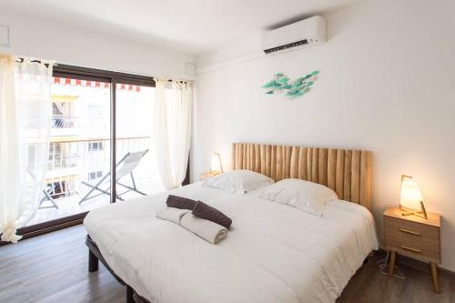 a bedroom with a large white bed and a window at M1 2P Vue Mer & Cap 1min plage AC Wifi balcon in Roquebrune-Cap-Martin