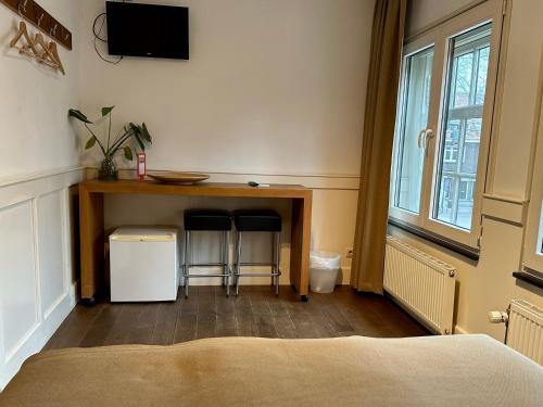 a bedroom with a table with two stools and a tv at Long John's Pub & Hotel in Amersfoort