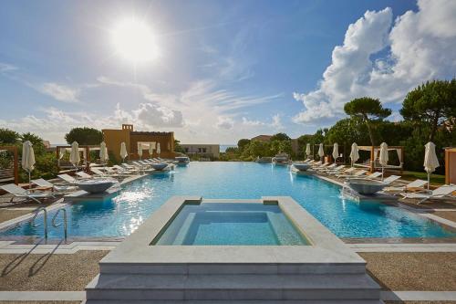 une grande piscine avec des chaises longues et une piscine dans l'établissement The Westin Resort, Costa Navarino, à Romanu