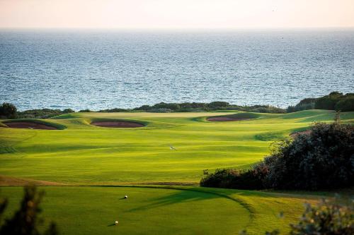 a green golf course with the ocean in the background at The Westin Resort, Costa Navarino in Romanós