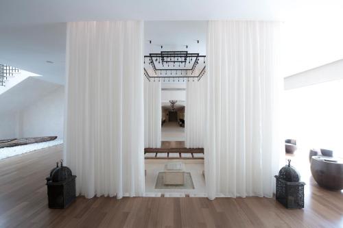 a white room with white curtains in a room at The Westin Resort, Costa Navarino in Romanós