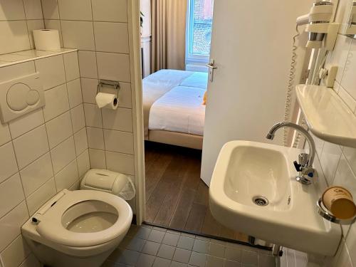 a small bathroom with a toilet and a sink at Long John's Pub & Hotel in Amersfoort