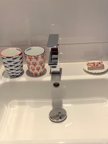 a counter with three cups on top of a sink at Appartement 't Zomerhuis in Zandvoort