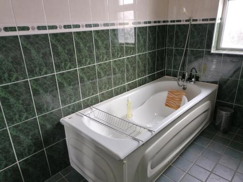 La salle de bains carrelée de couleur verte est pourvue d'une baignoire. dans l'établissement Atlantic Way Farmhouse, à Lahinch