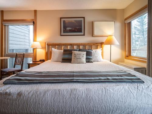 a bedroom with a large bed and two windows at Caribou Highlands Lodge in Lutsen