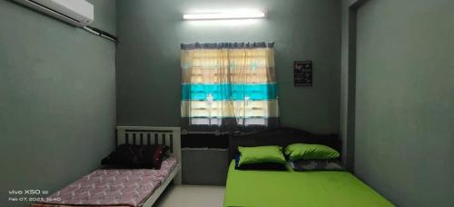 a bedroom with a green bed and a window at Homestay Lumut in Lumut