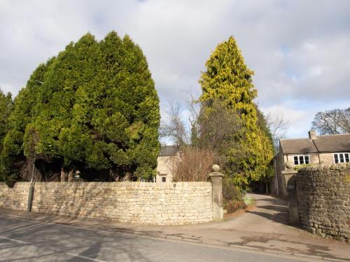a stone fence and trees in front of a house at The Beeches - Chatsworth Apartment No 2 - Sleeps 4 in Baslow