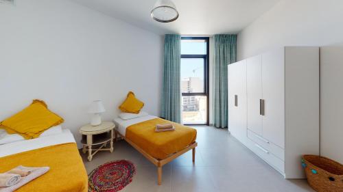 a bedroom with two beds and a table and a chair at St Julians Central luxury apartment in St. Julianʼs