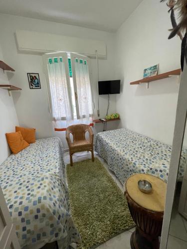 una camera con due letti, un tavolo e una sedia di Giuly's Room a Porto Santo Stefano