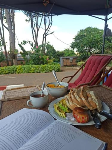 una mesa con un plato de comida y un libro en Chez Jeanne Auberge en Talata-maty