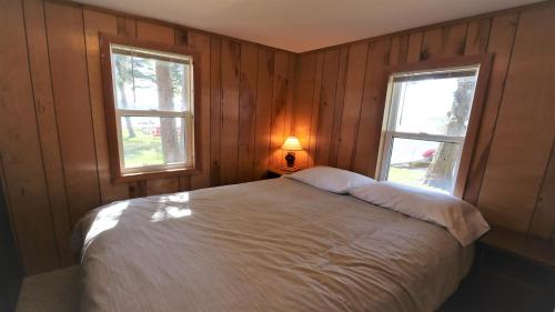 a bedroom with a white bed and two windows at Sunset Shore in Petoskey