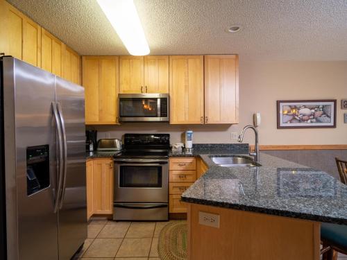 a kitchen with stainless steel appliances and wooden cabinets at Caribou Highlands Lodge in Lutsen