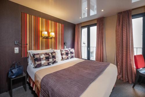 a hotel room with a bed and a balcony at Hôtel Du Vieux Saule in Paris