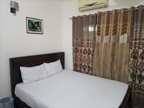 拉合爾的住宿－Star Hotel Lahore，一间卧室配有床和窗帘