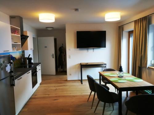 a kitchen and dining room with a table and a television at Quartier No. 7 - Serviced Living in Grödig
