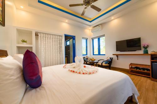 a bedroom with a white bed with a ceiling fan at LOCAL BEACH FRONT VILLAS in Tân Thành (1)