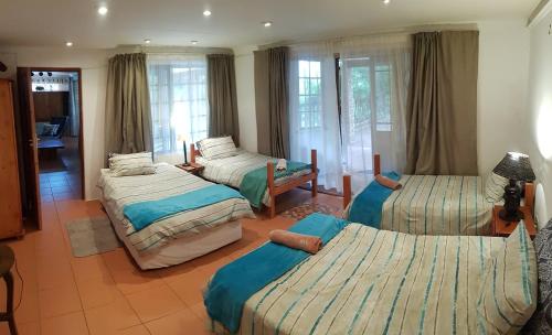 a bedroom with three beds in a room with windows at Acra-Retreat Mountain View Lodge in Waterval Boven